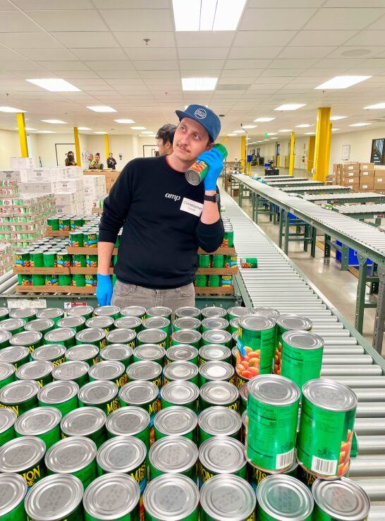 Person playfully holding a can to their ear like a phone while standing in a warehouse.