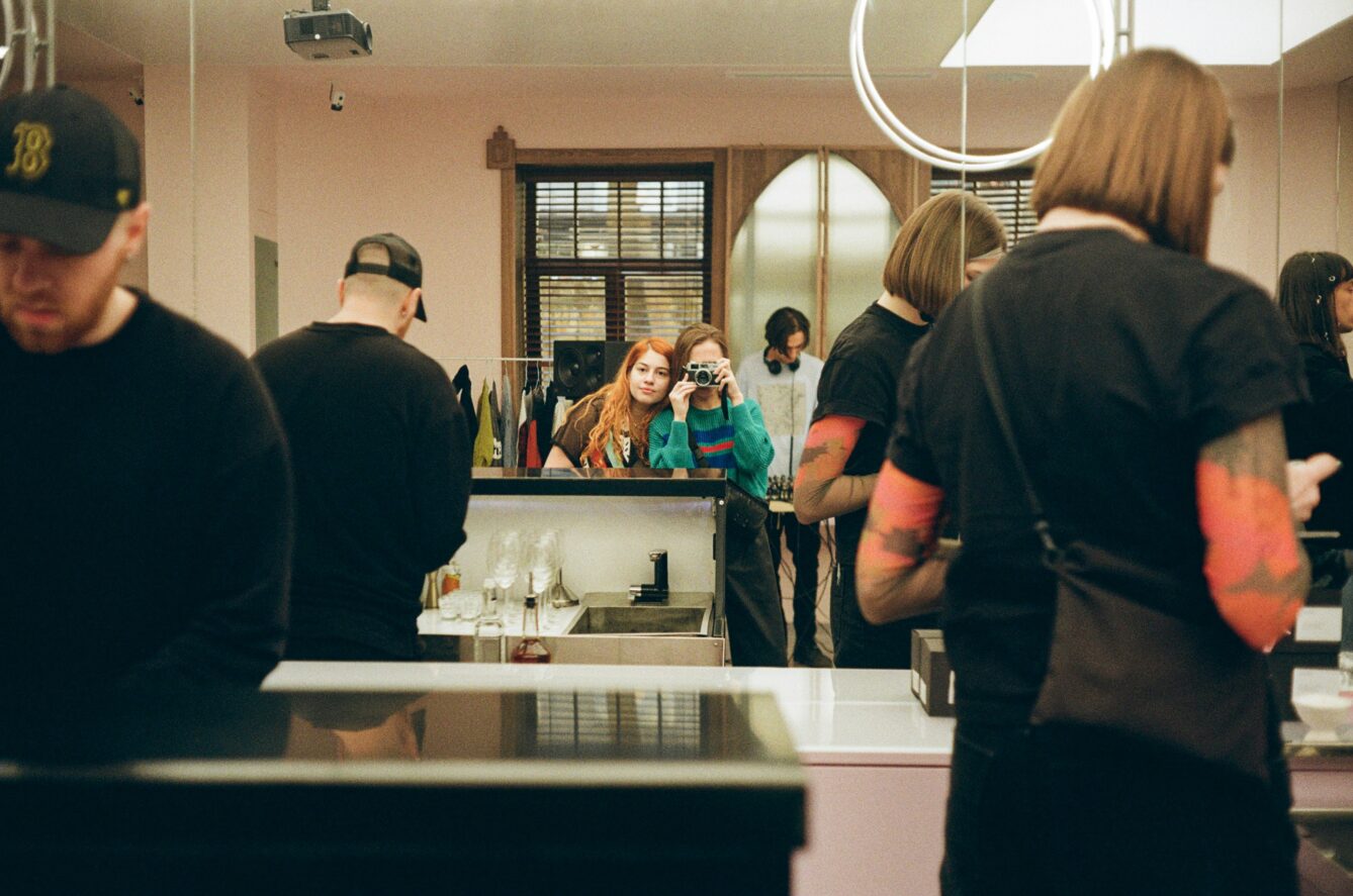 Girls taking a photo with a film camera in a mirror